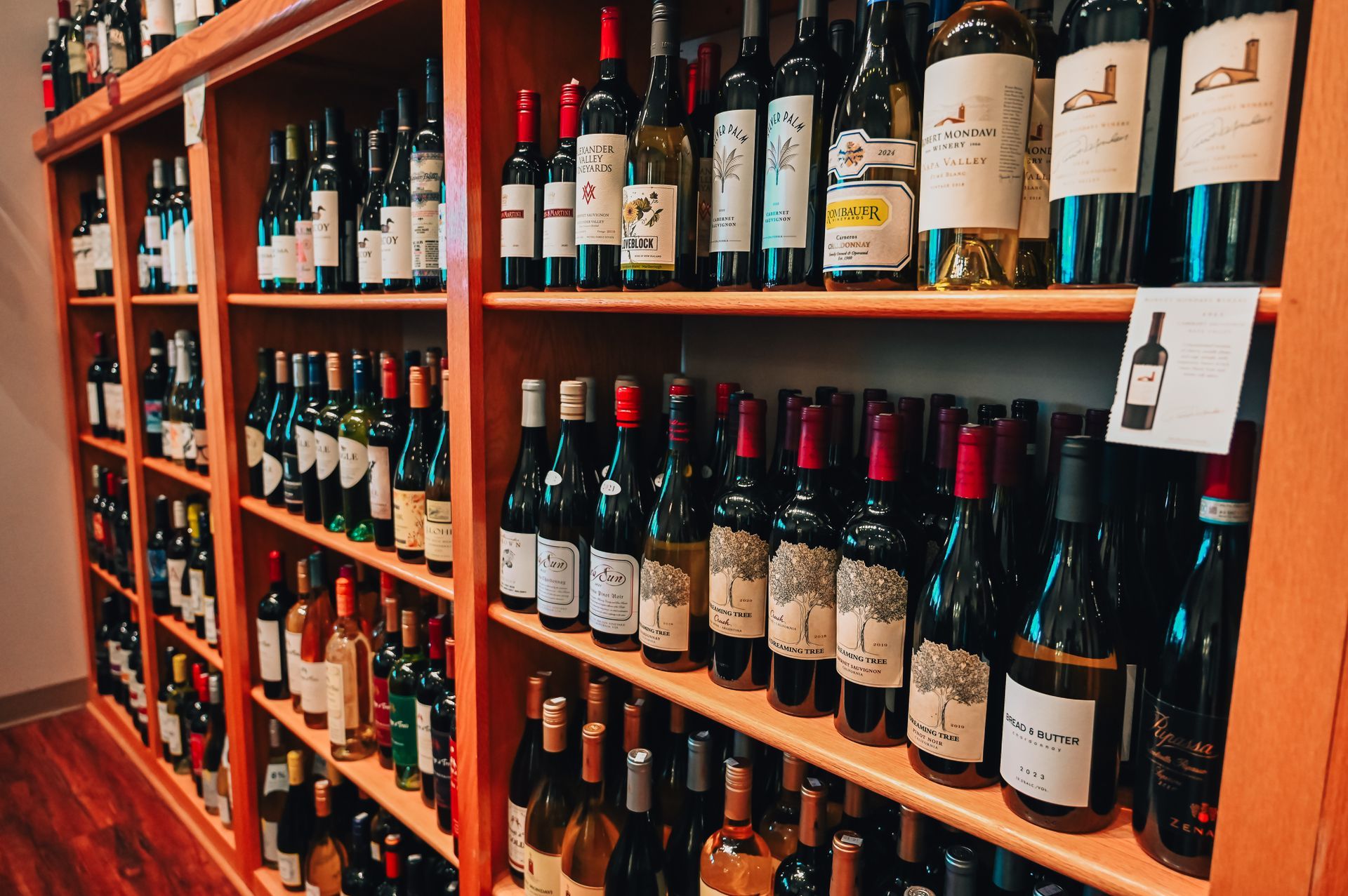 Wine bottles displayed on wooden shelves in a shop.