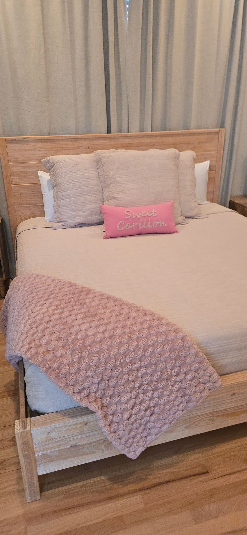 A bed with a pink blanket and pillows in a bedroom.