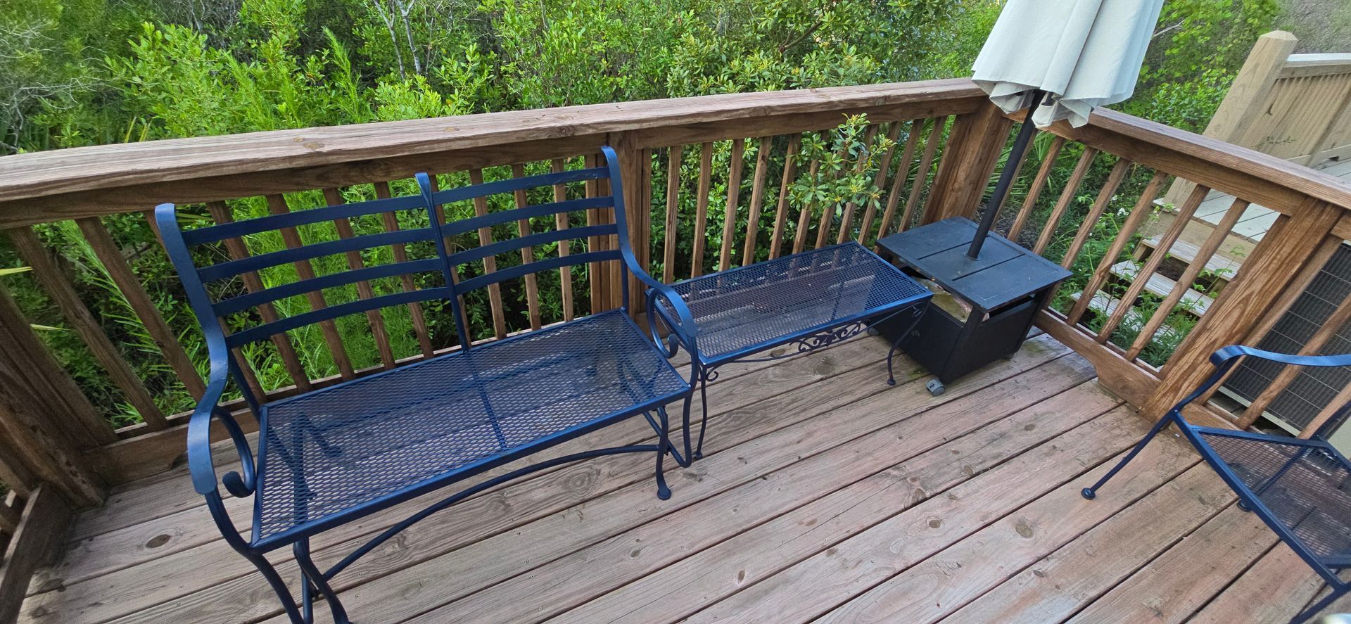 A wooden deck with a bench and chairs on it.