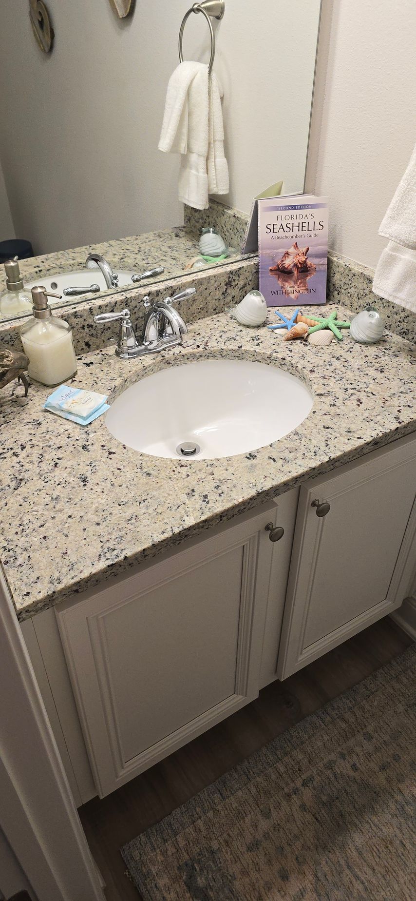 A bathroom sink with a granite counter top and a mirror.