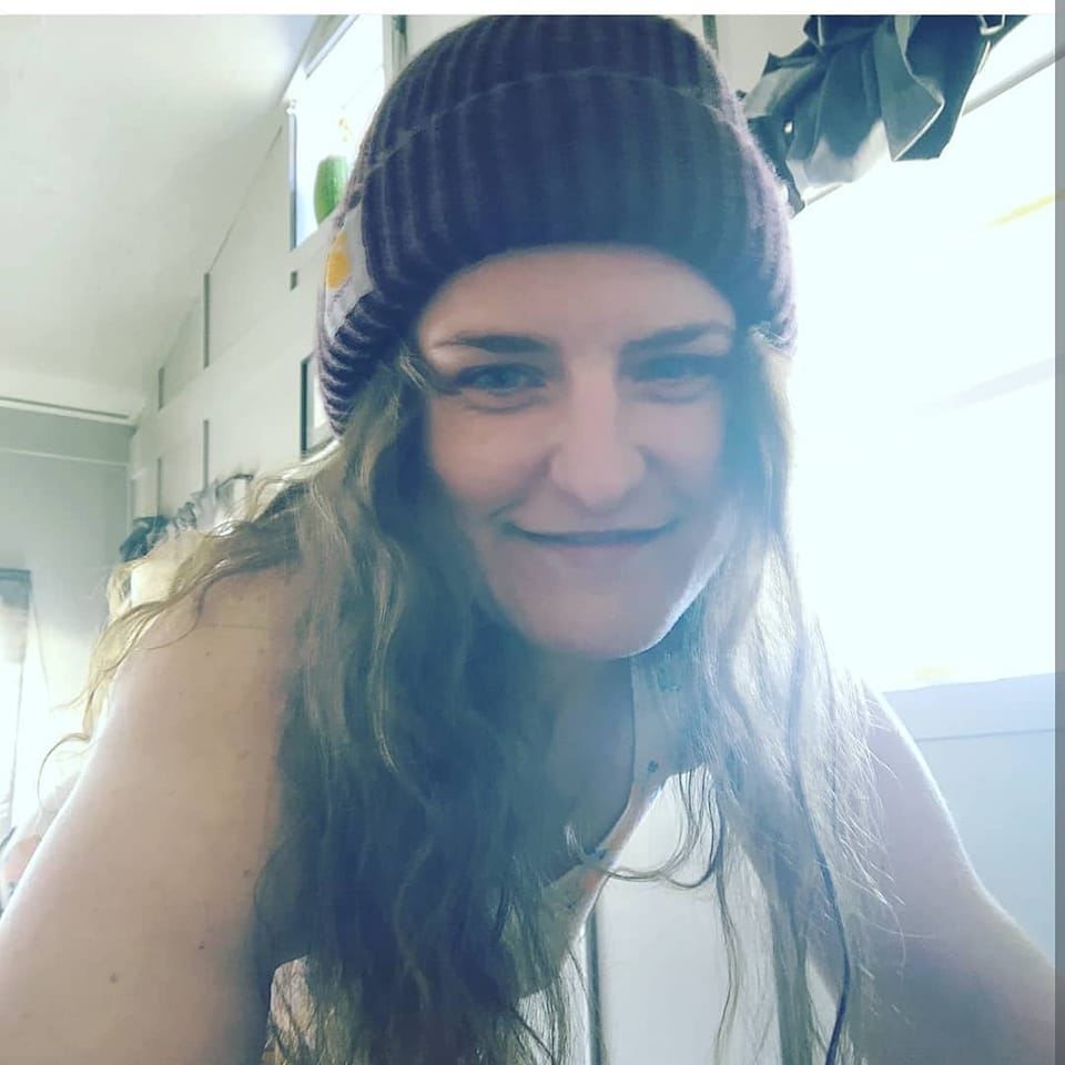 A woman wearing a purple beanie is smiling for the camera