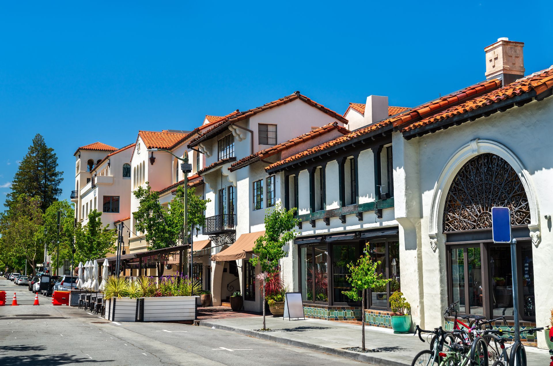 Street view of shops and businesses, buildings with orange tiled roofs, sunny day.