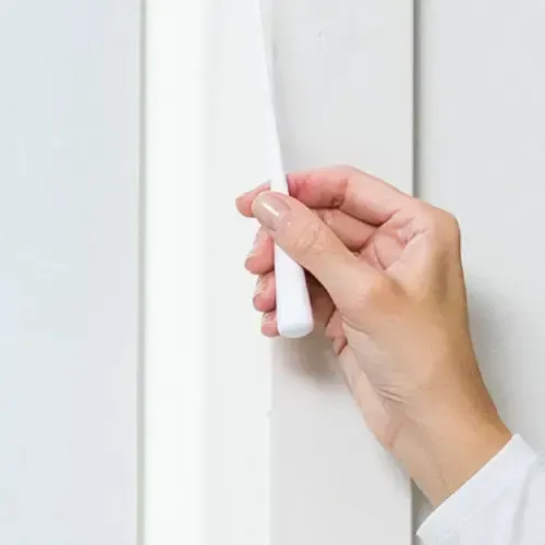 Hand pulling a white vertical blind cord.