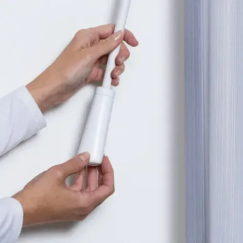 Hands assembling a white roller blind, connecting the handle to the roller.