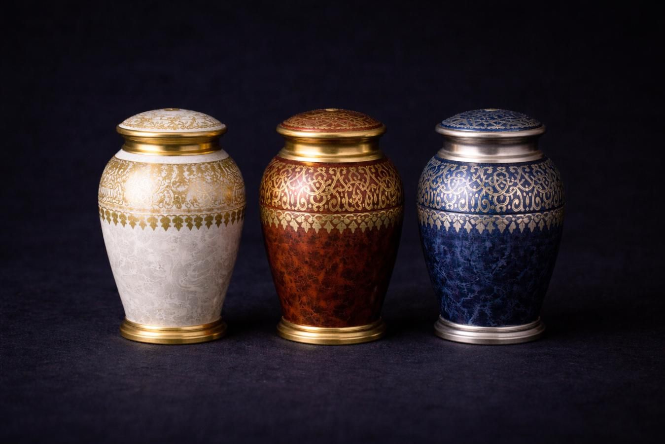 Three ornate cremation urns in white, red, and blue with gold detailing, symbolizing dignified options for direct cremation Albuquerque, NM services.