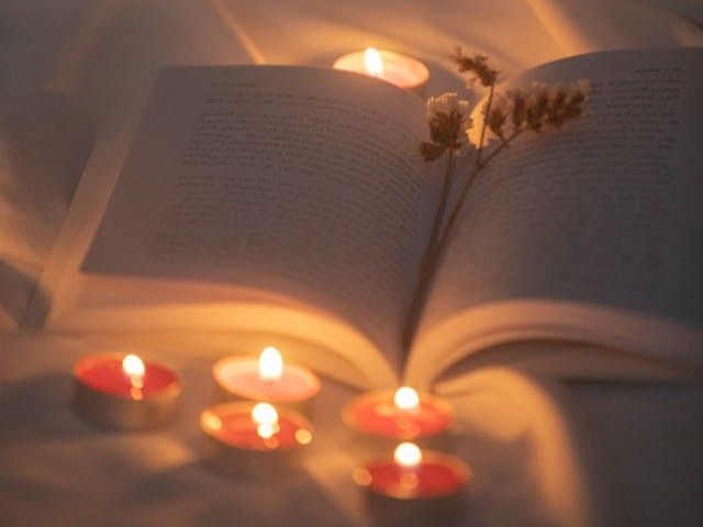 Glowing tealight rests on an open book beside dried flowers with direct cremation in Rio Rancho, NM