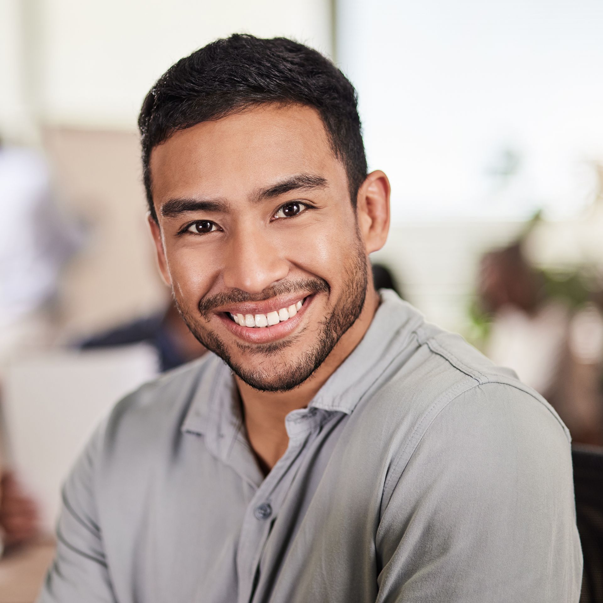 Smiling man in a gray shirt in a bright indoor setting