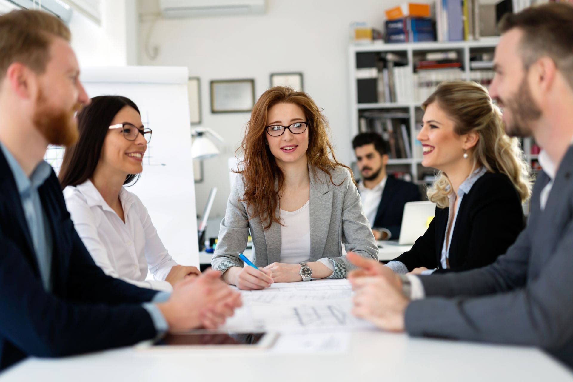 Colleagues in a meeting around a conference table, discussing documents in a bright office
