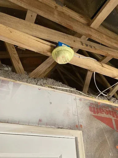 Tennis ball lodged in ceiling beams near electrical box and insulation.