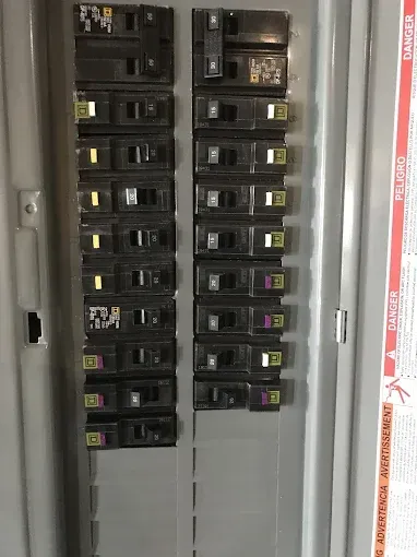 Electrical circuit breaker panel with black switches, some in the on position, inside a gray metal box.