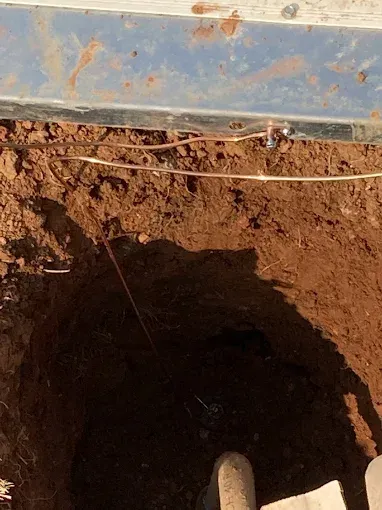 Close-up of a dirt hole with thin wire running across the top.