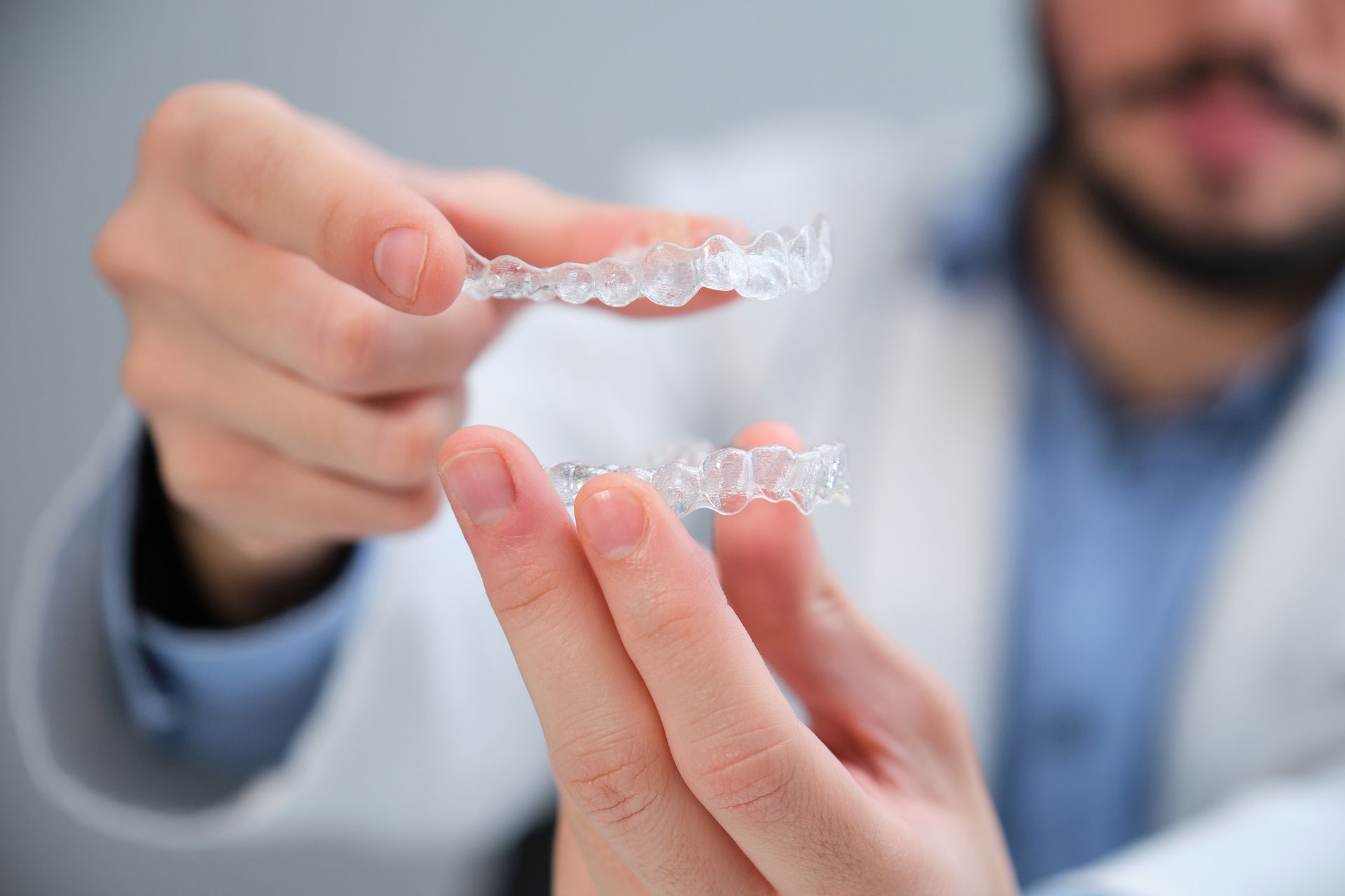 Dentist holding two clear aligners for teeth. Dentist holding two clear aligners for teeth.