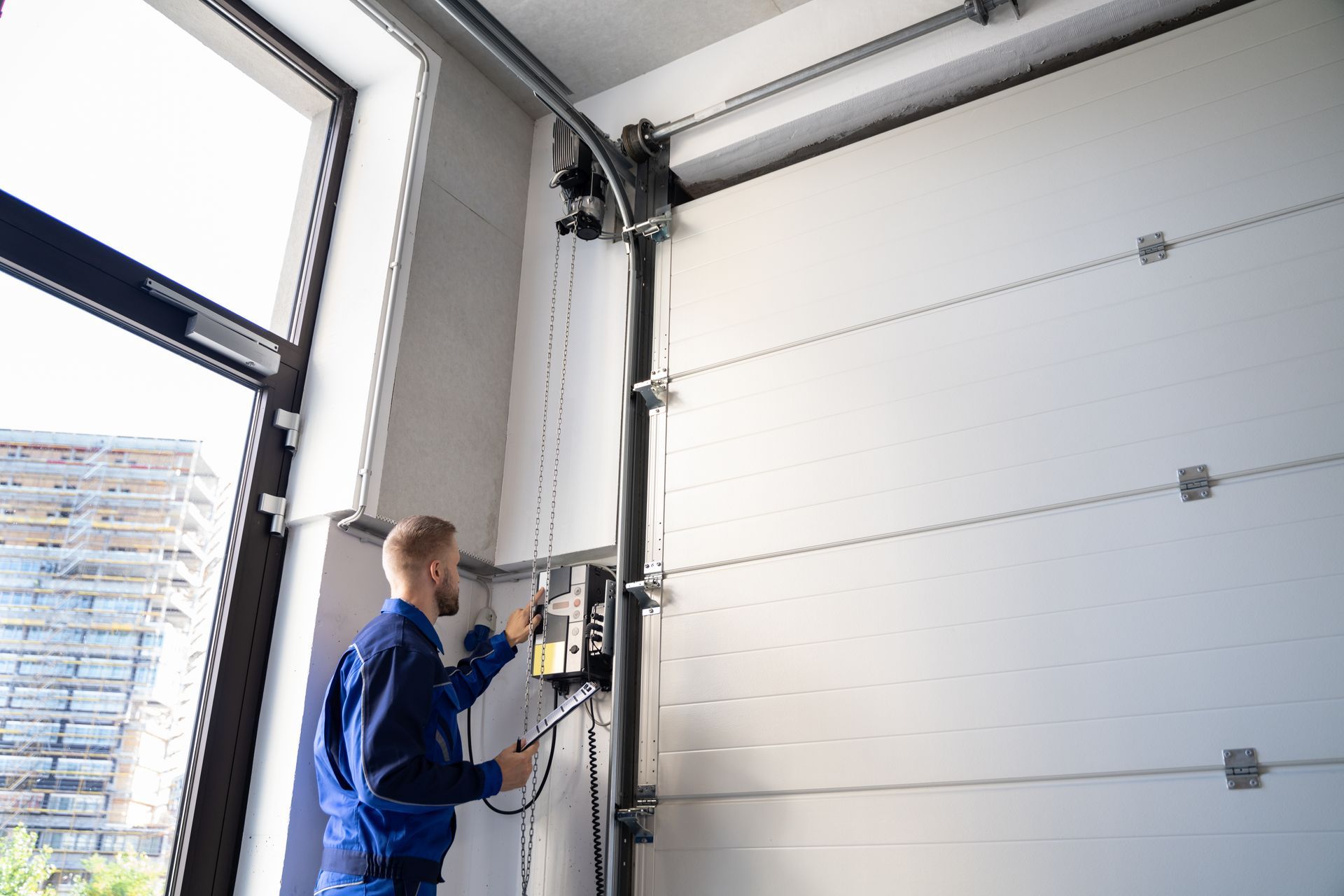 A Technician adjusting the controls of a garage door opener during a maintenance check.