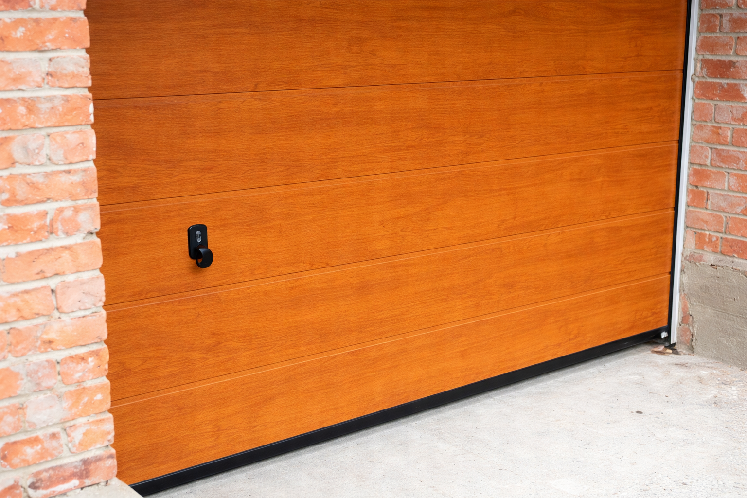 Woodgrain garage door closed between brick walls, modern residential wooden garage door exterior new.
