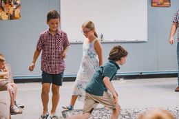 People worshiping with arms raised, some looking upwards, inside a building with natural light.