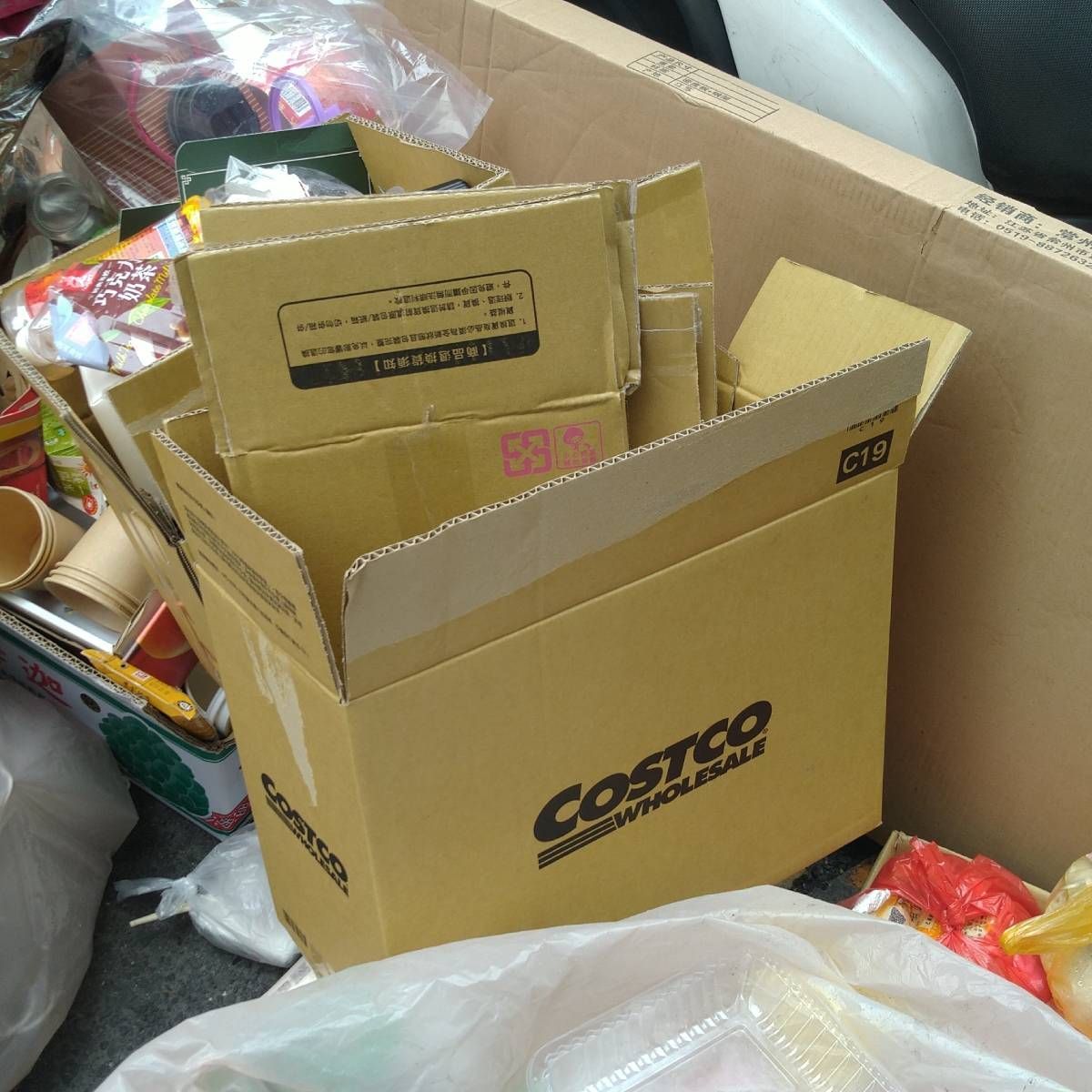 Cardboard boxes, including a Costco box, filled with other boxes and trash.