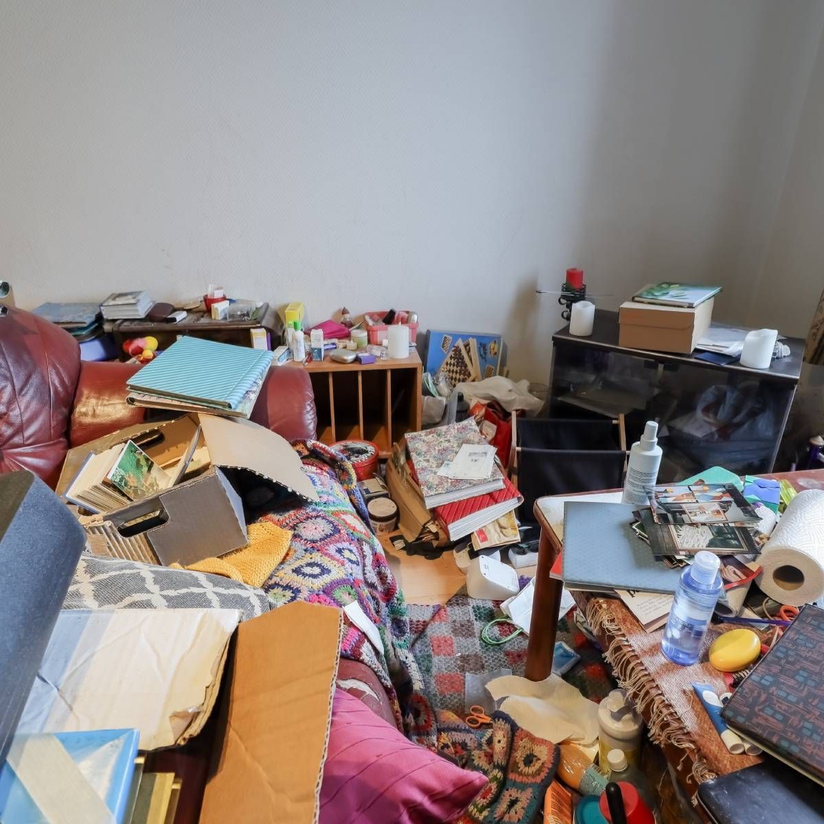 Messy living room with cluttered furniture and various items scattered around.