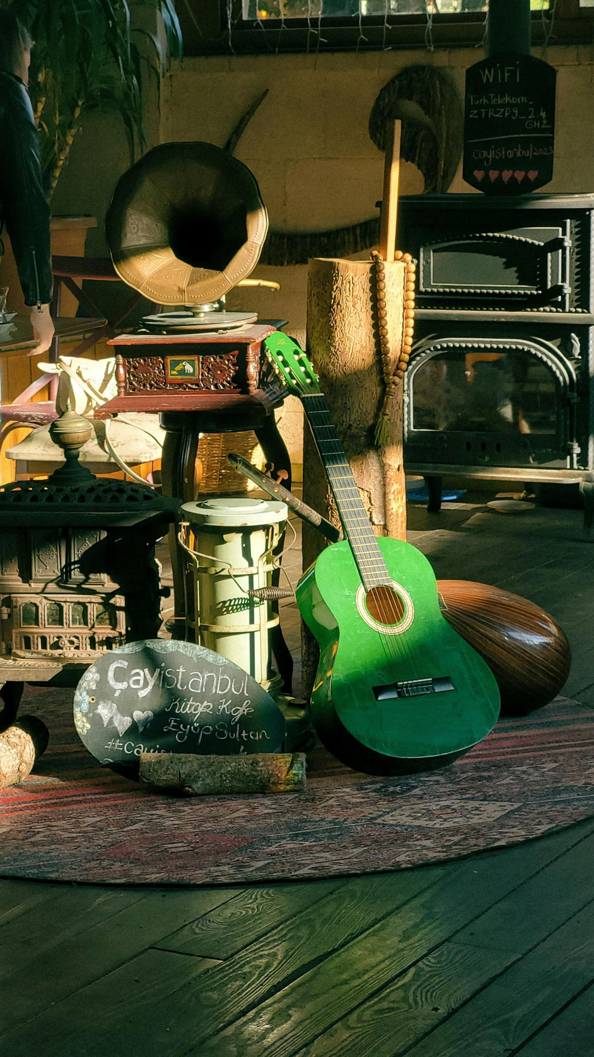An eclectic collection of musical instruments and decor on a rug, including a green guitar, and a record player.