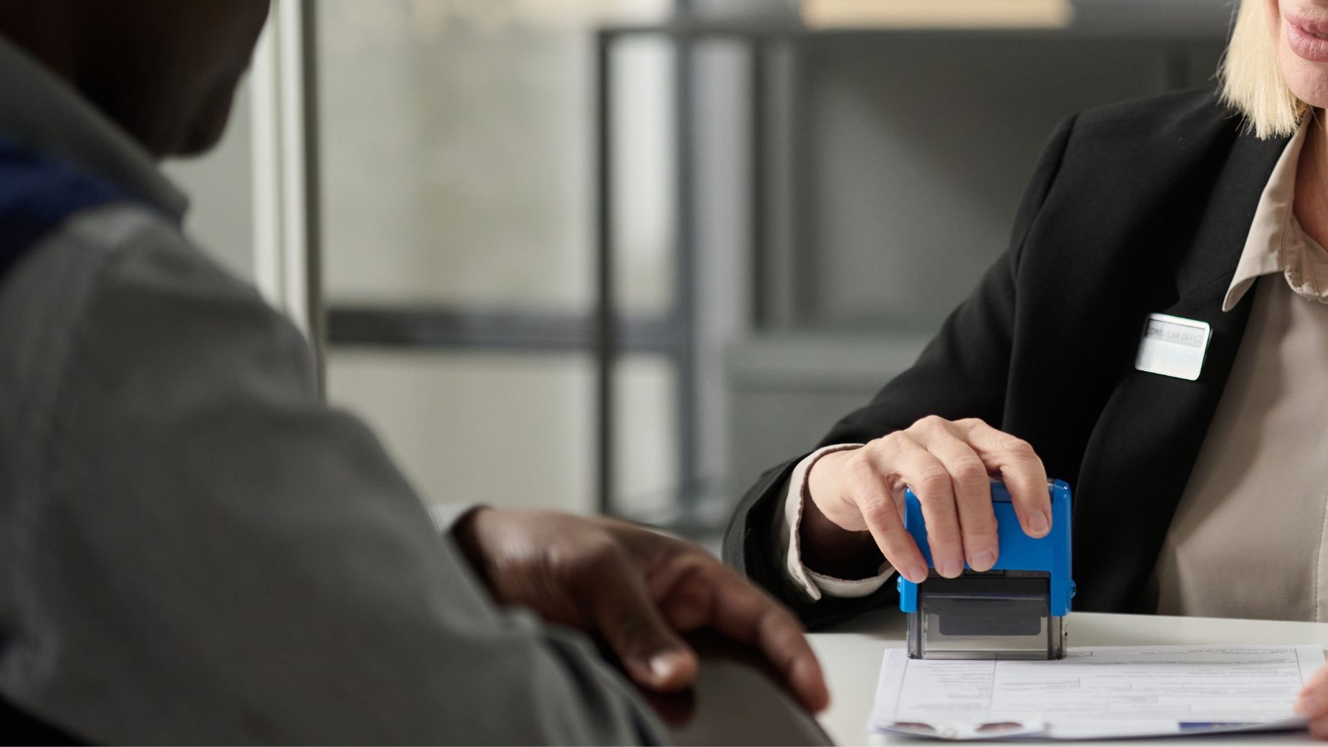 A woman is stamping a document on a man 's hand.