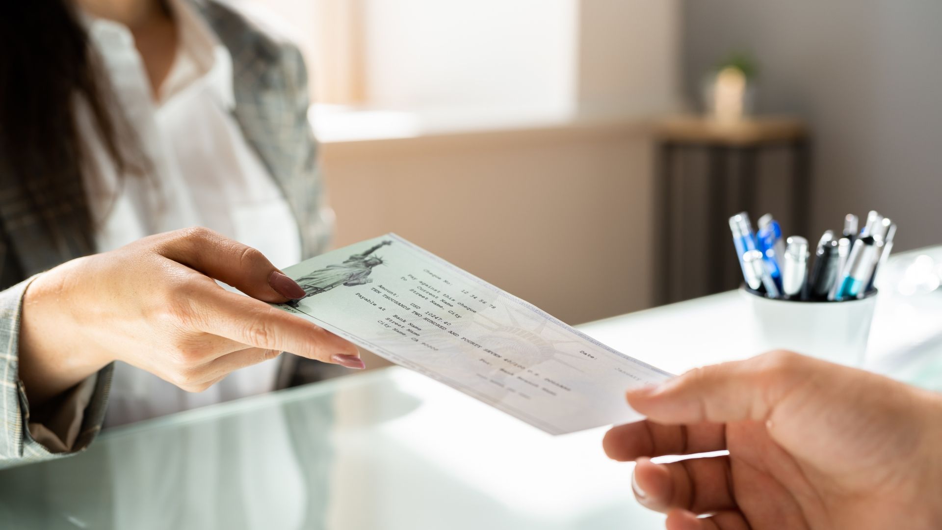 A man is handing a check to a woman at a reception desk.