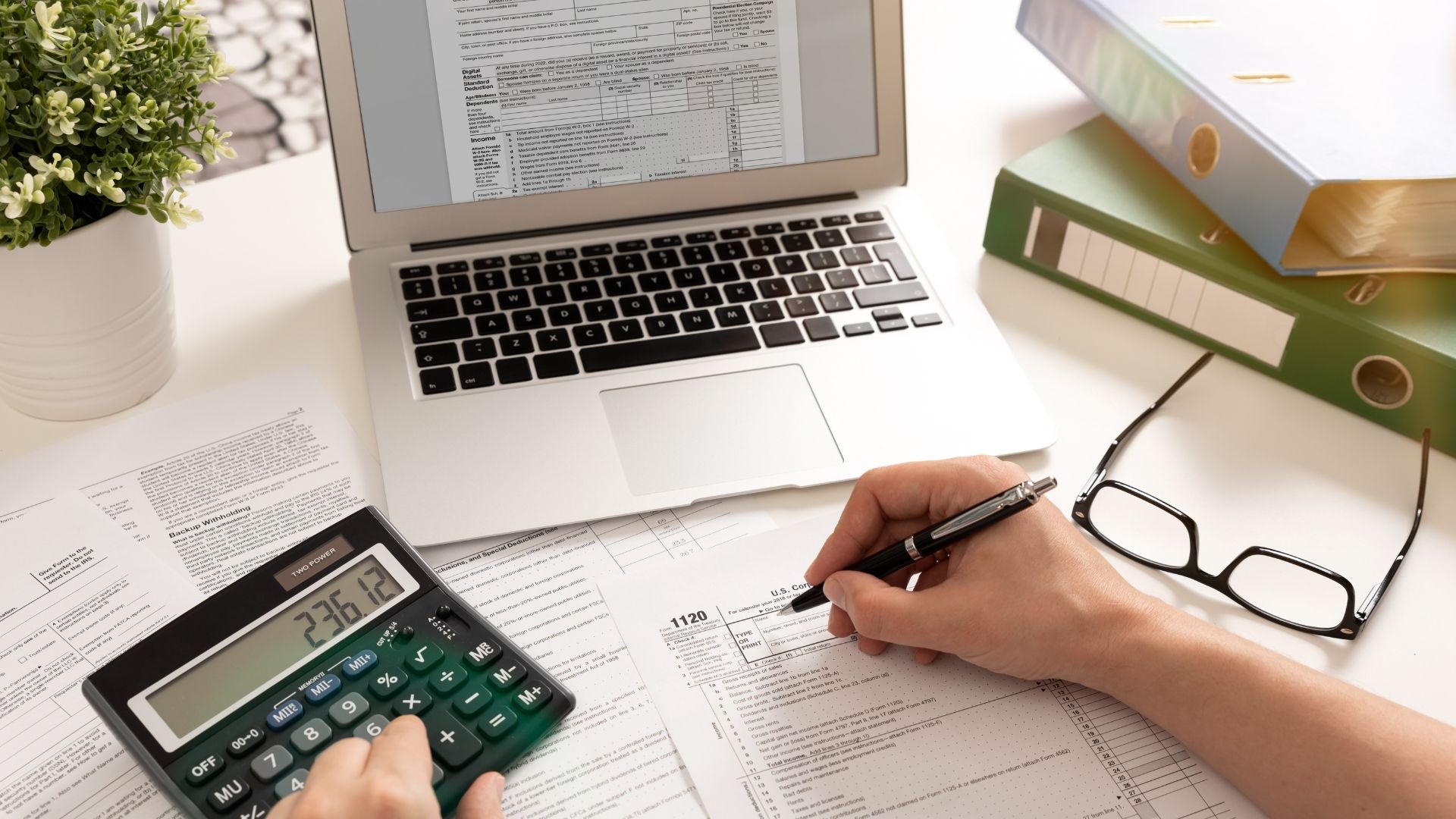 A person is using a calculator and writing on a piece of paper.