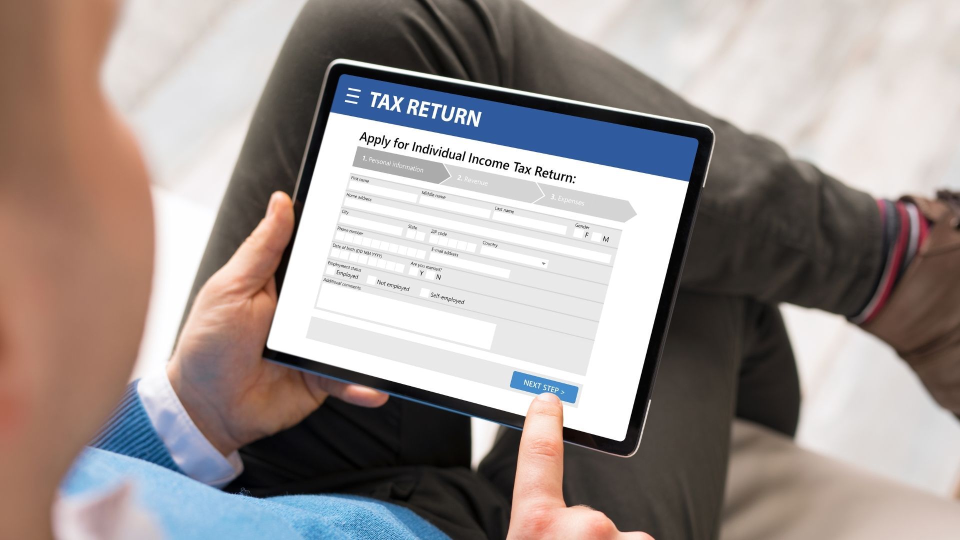 A man is using a tablet to fill out a tax return form.