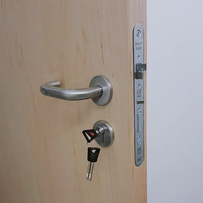 Close-up View Of An Office Wooden Door Equipped With A Silver Handle And Keyed Deadbolt Lock. Close-up View Of An Office Wooden Door Equipped With A Silver Handle And Keyed Deadbolt Lock.