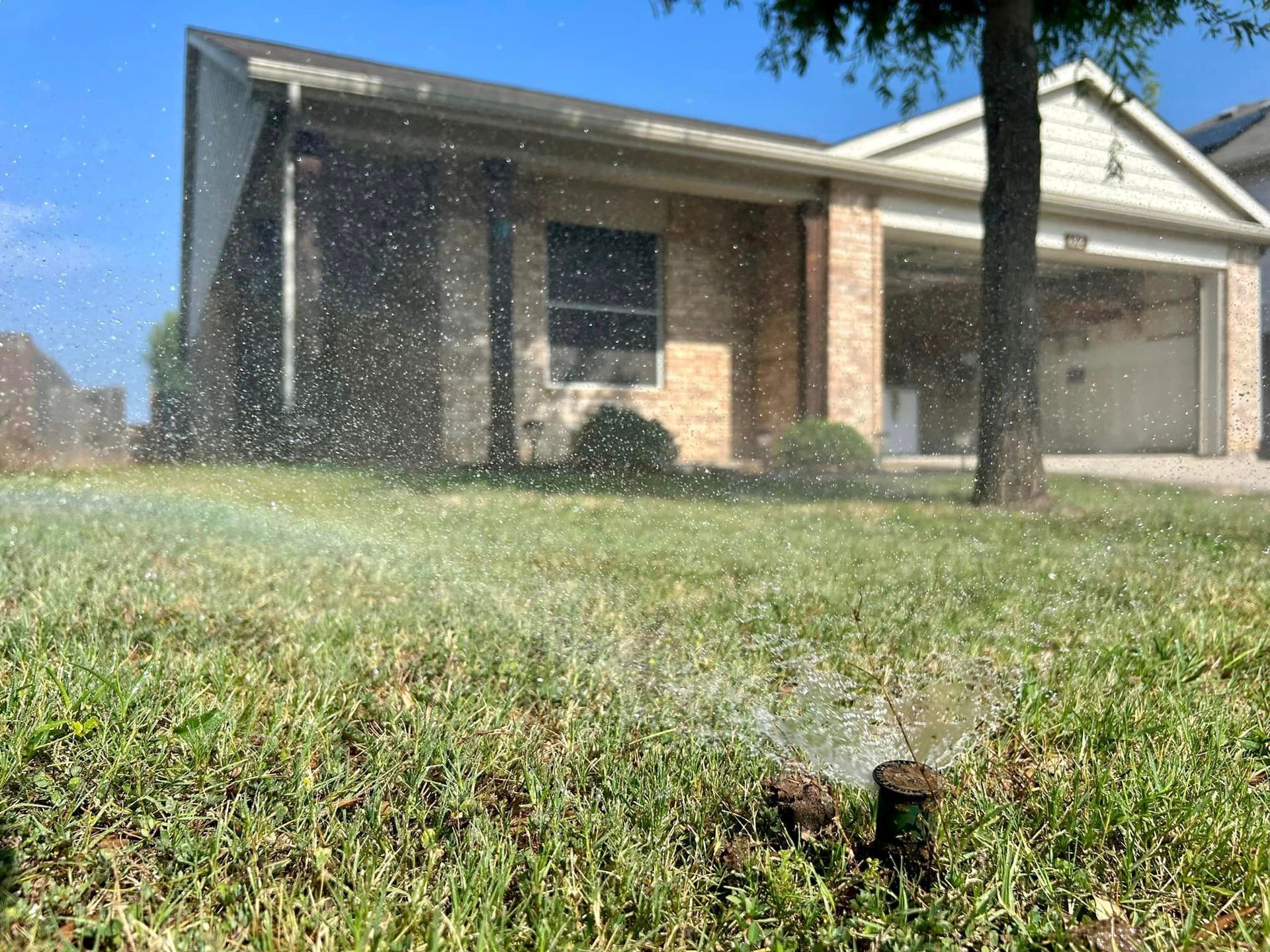 A Lawn Sprinkler Is Spraying Water on A Lush Green Lawn in Front of A House - Collinsville, TX - L5 Irrigation