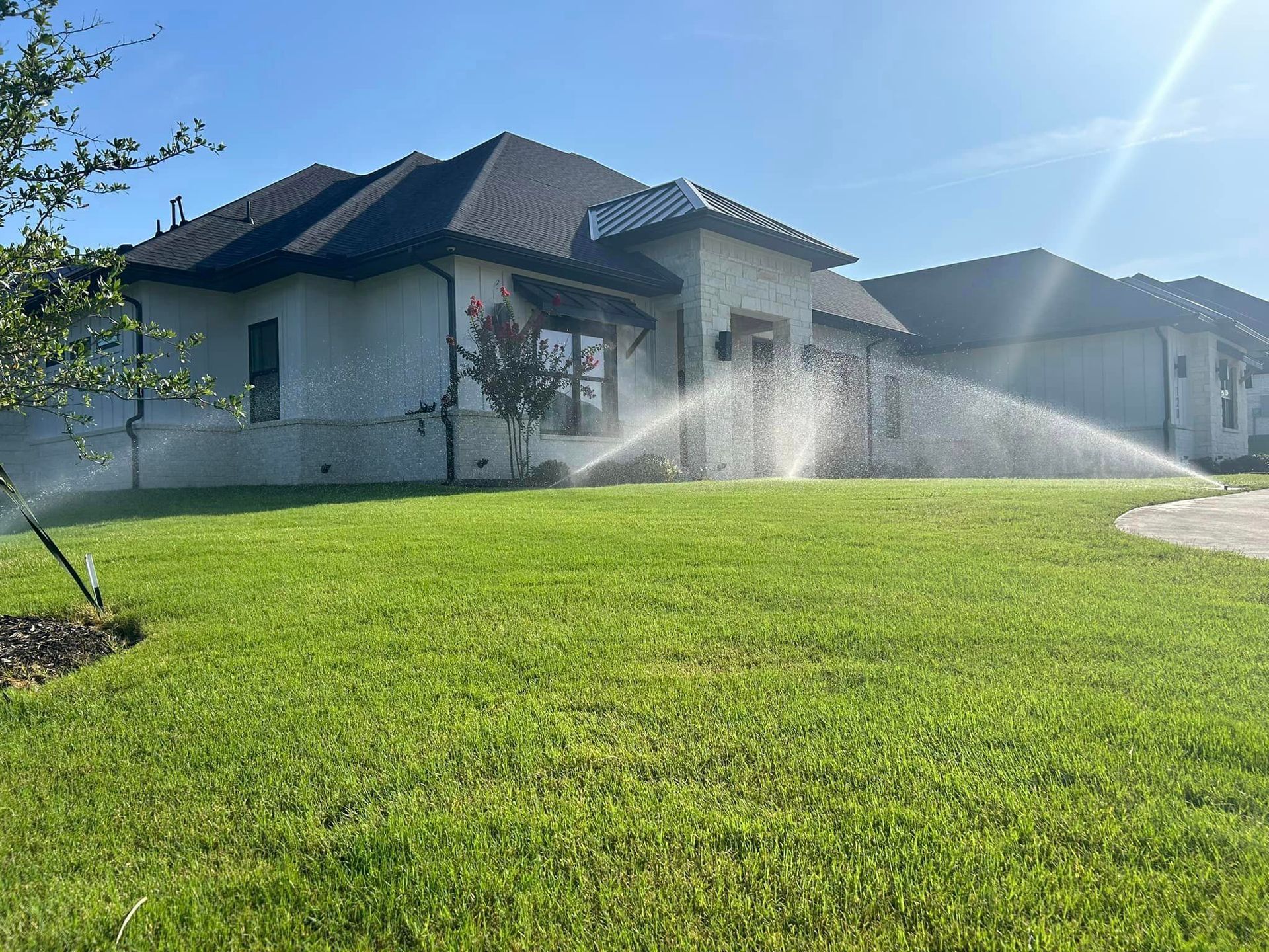 A Sprinkler Is Spraying Water on A Lush Green Lawn in Front of A House - Collinsville, TX - L5 Irrigation