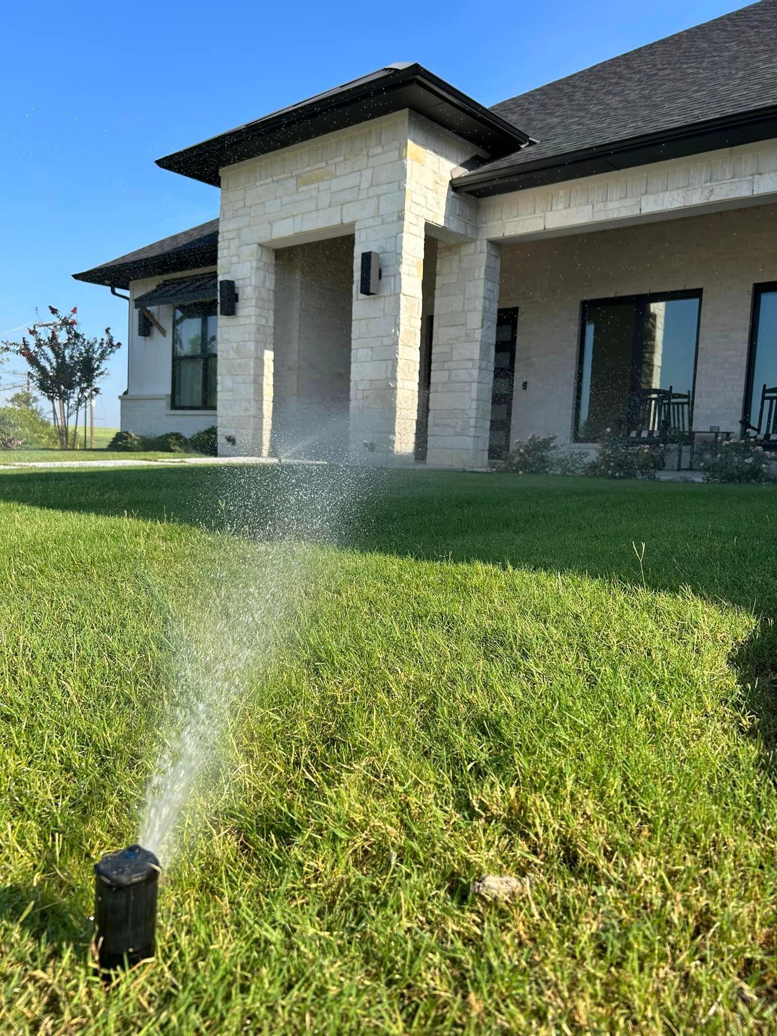A Person Is Spraying Water on A Lawn in Front of A House - Collinsville, TX - L5 Irrigation