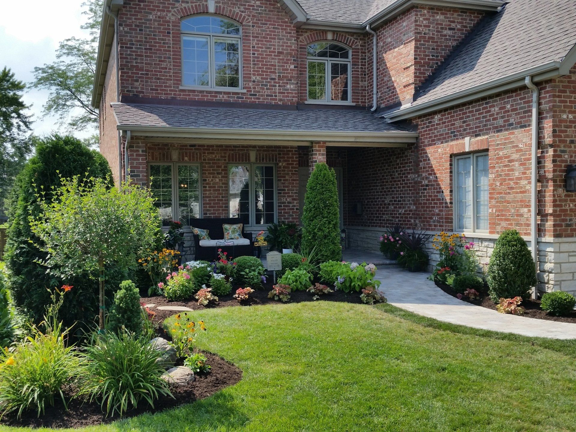 A large brick house with a lush green lawn in front of it.