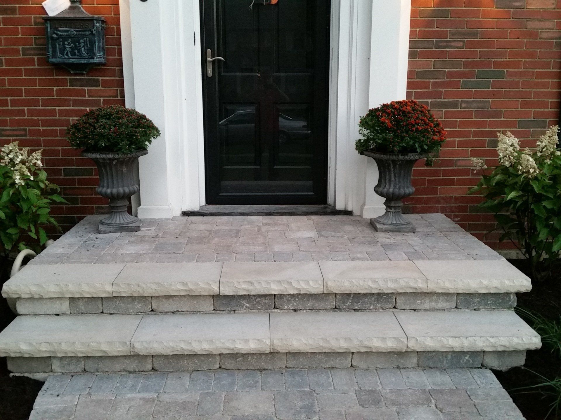 The front door of a brick house has a mailbox with the address 1813 on it