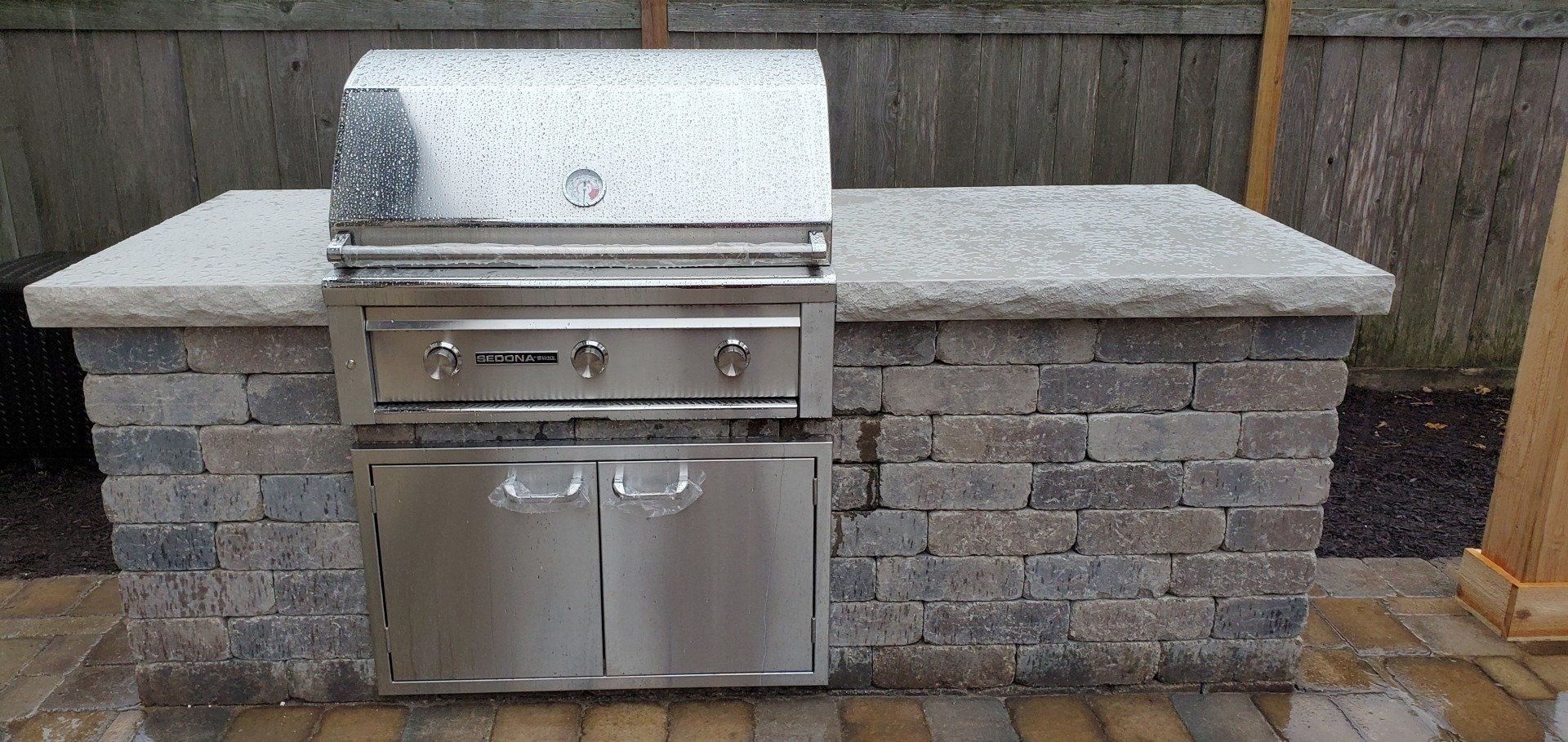 A stainless steel grill is sitting on top of a brick counter.