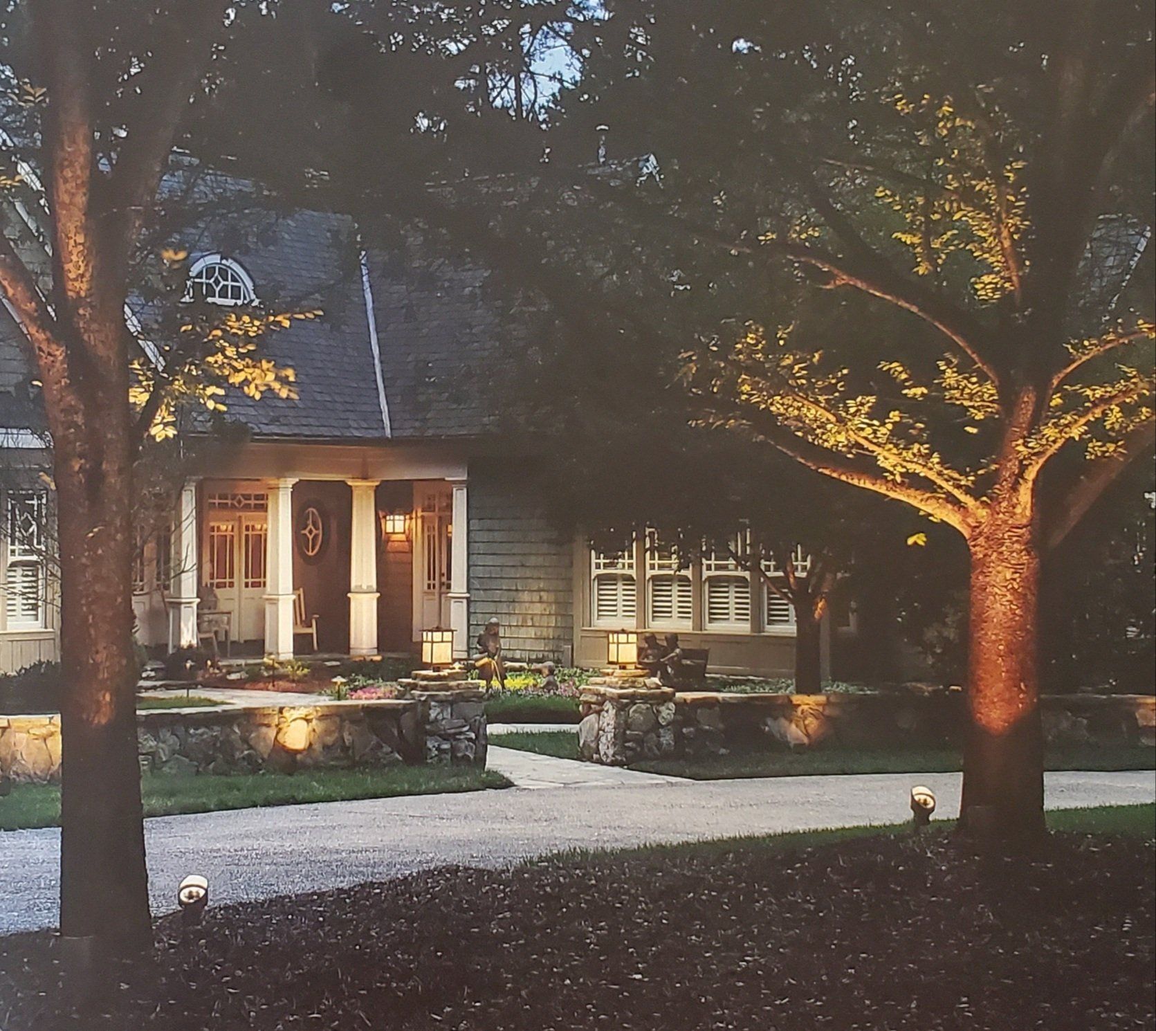 A house is lit up at night with trees in front of it