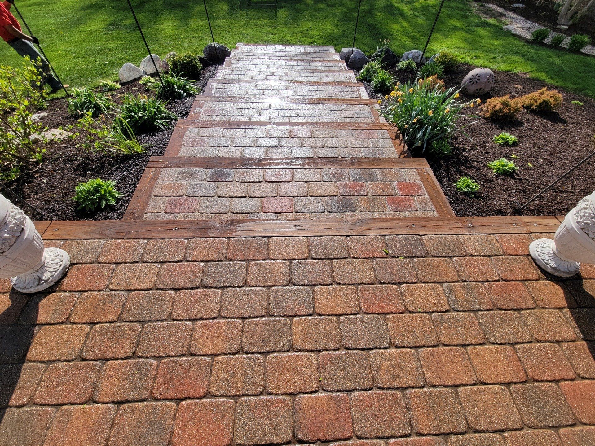 A brick walkway leading up to a lush green garden.