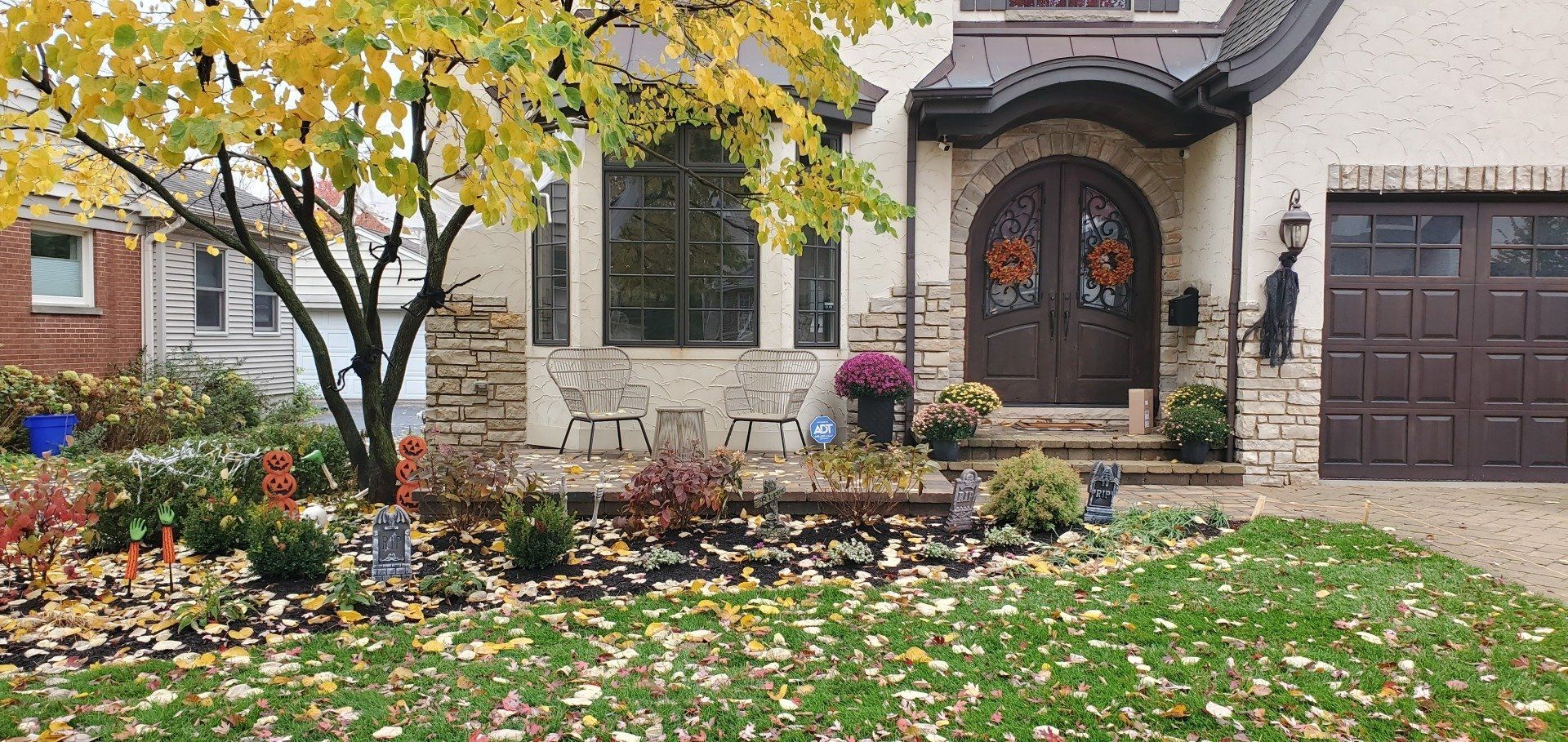 A house with a tree in front of it and a lot of leaves on the ground.