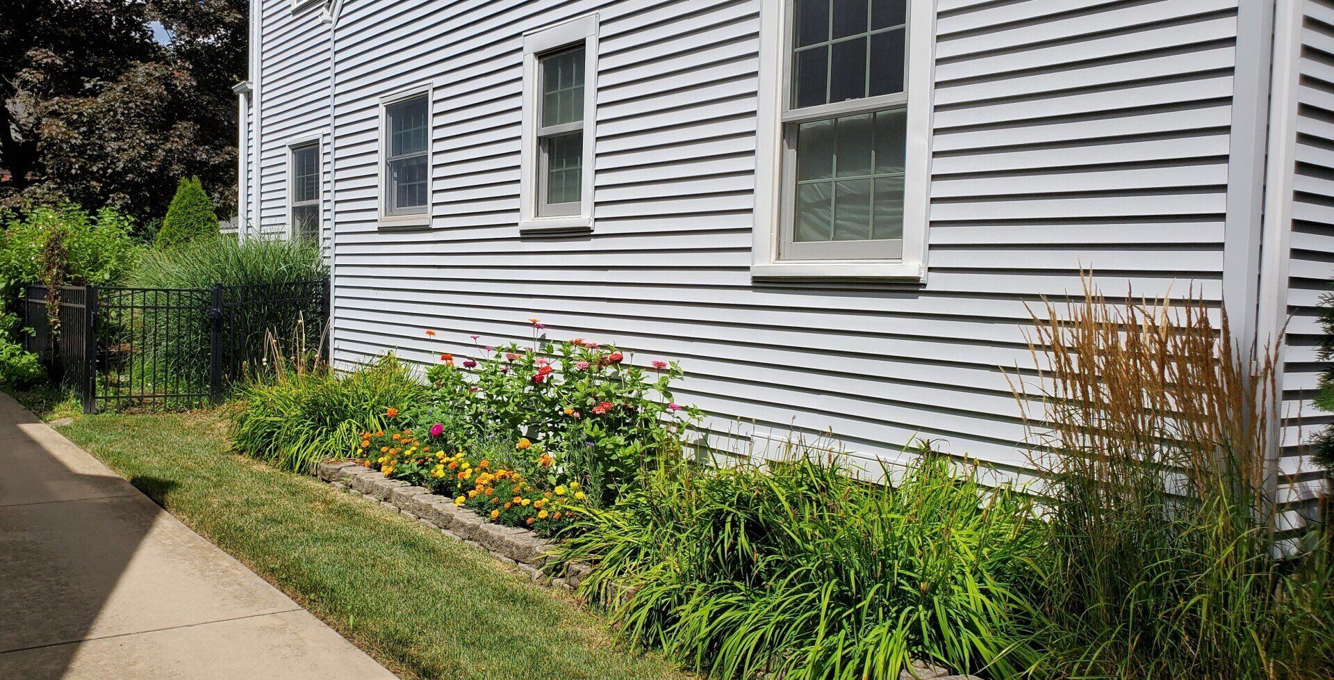 A white house with a sidewalk and flowers in front of it.