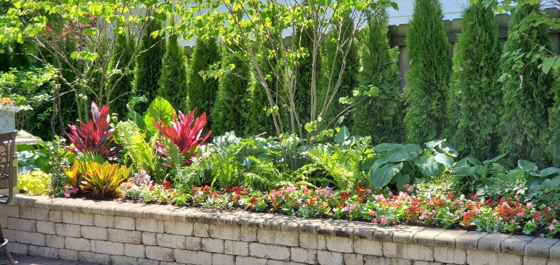 A brick wall surrounded by flowers and trees in a garden.