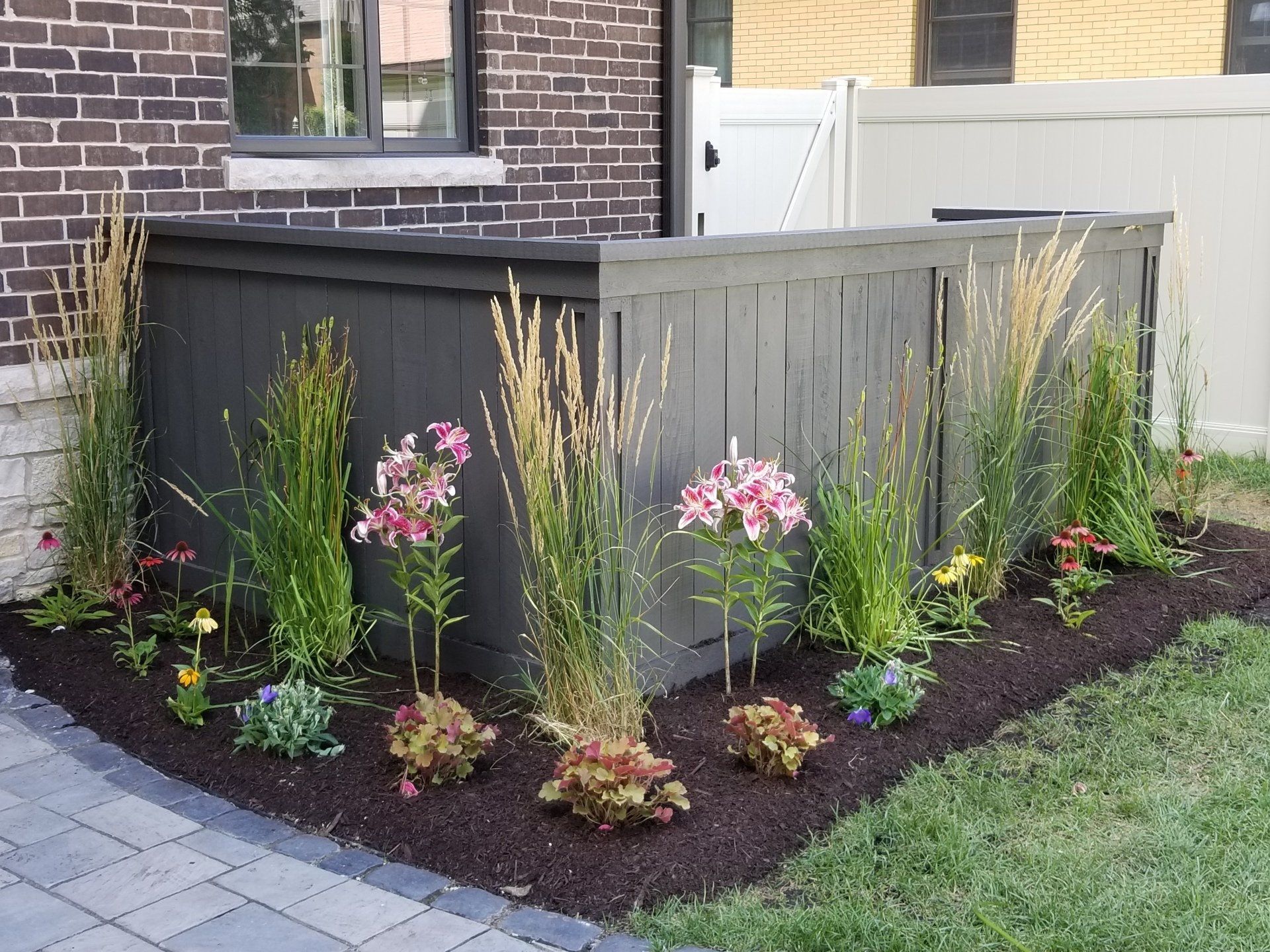 A garden with flowers and plants in front of a brick building
