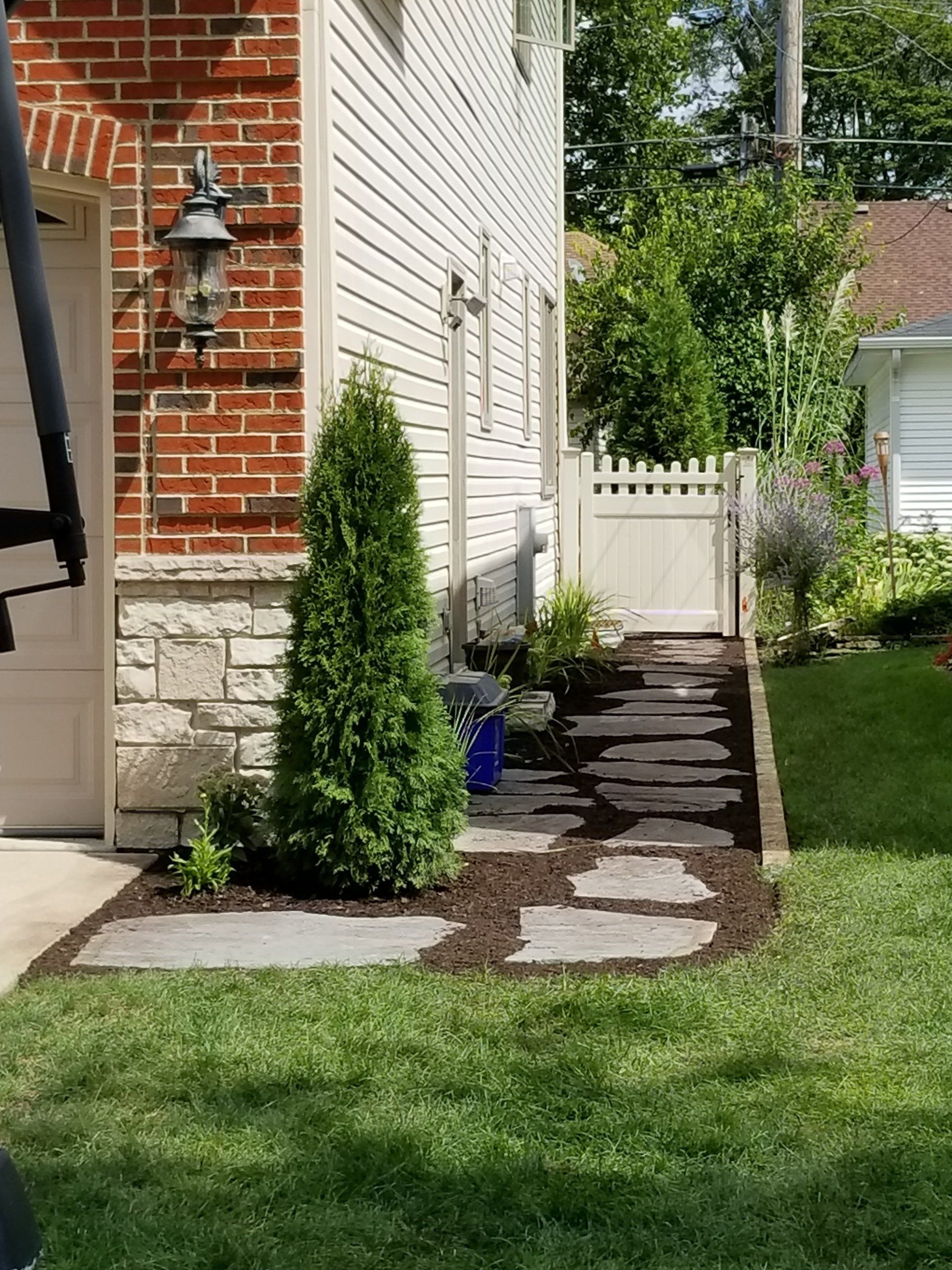 A stone walkway leading to a house with a white gate.
