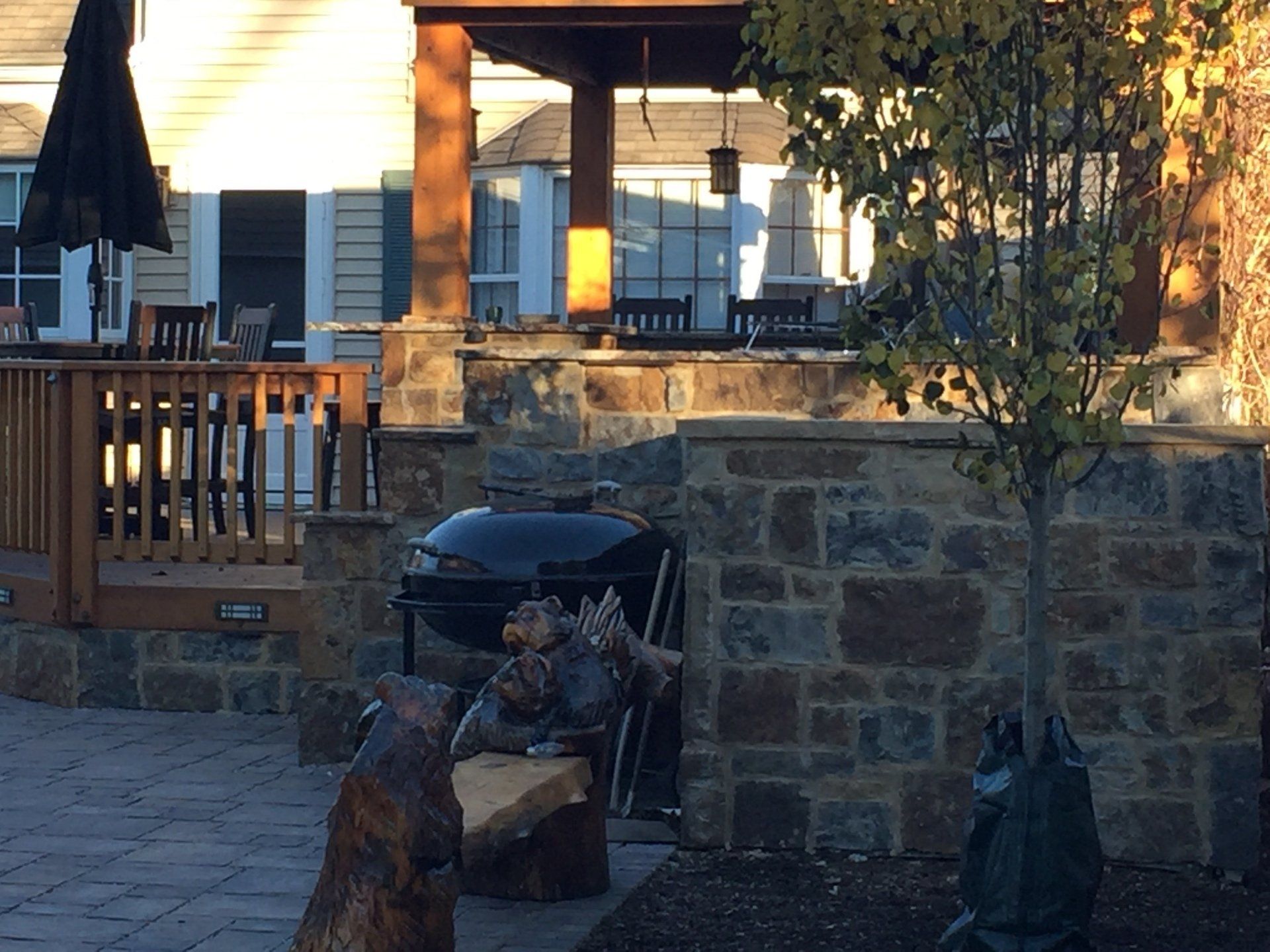 A bear statue sits on a bench in front of a grill