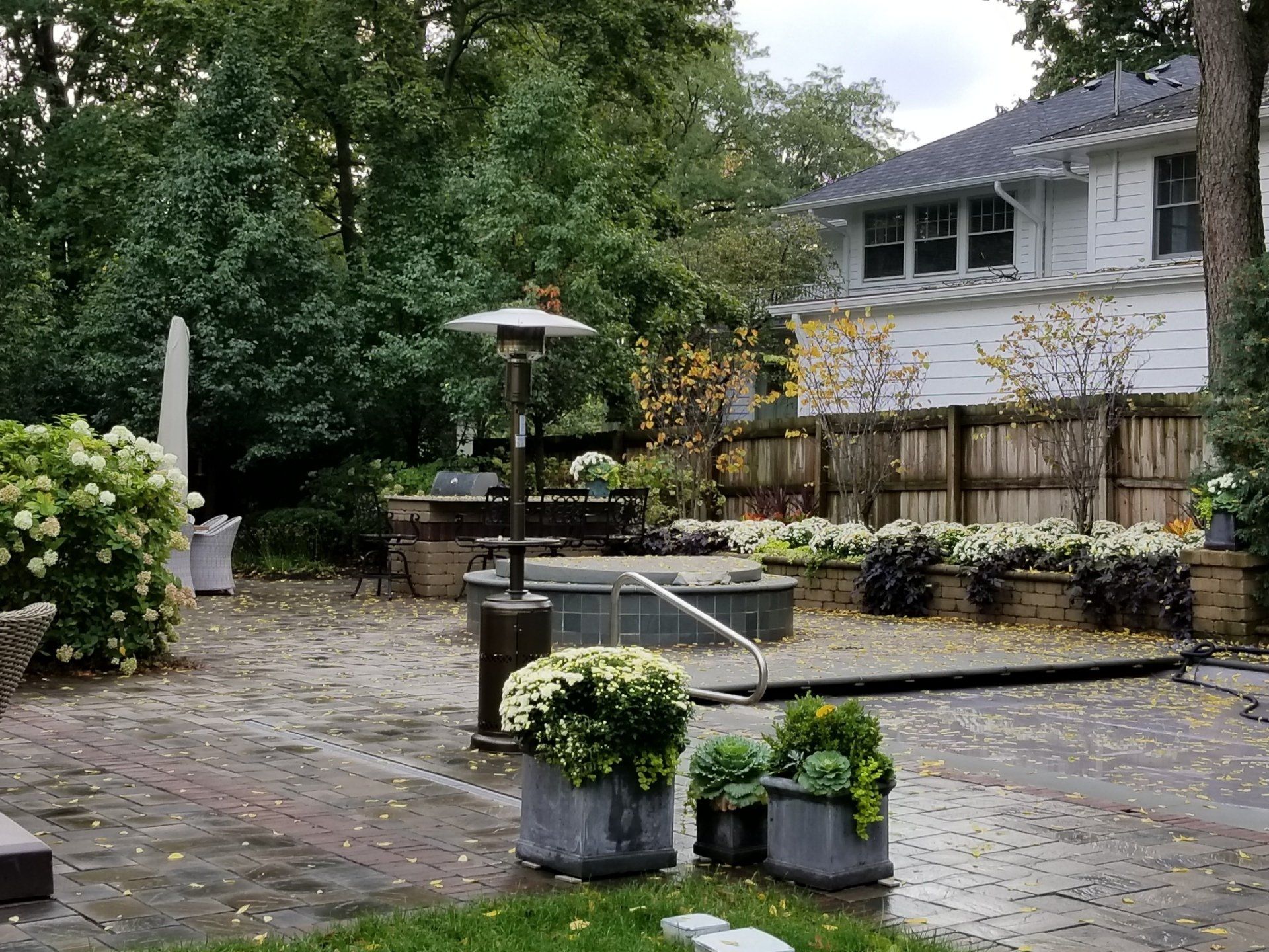 A patio with a heater and potted plants in front of a house.