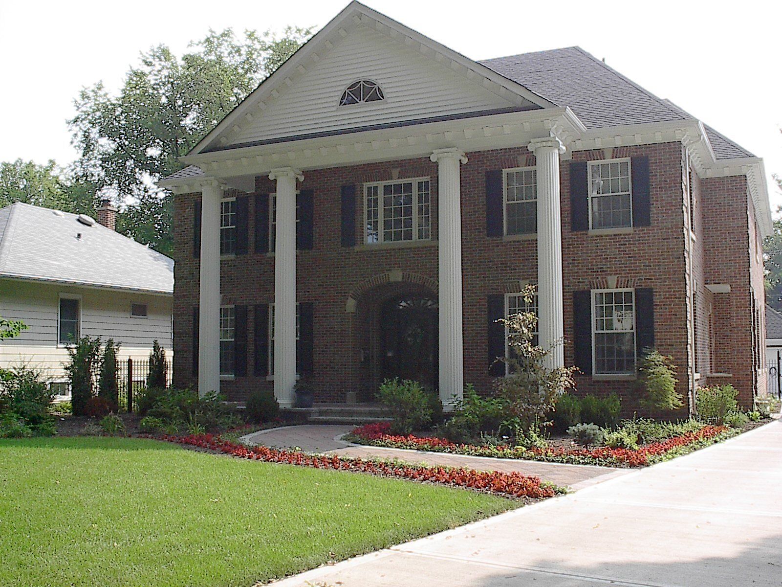 A large brick house with columns and black shutters