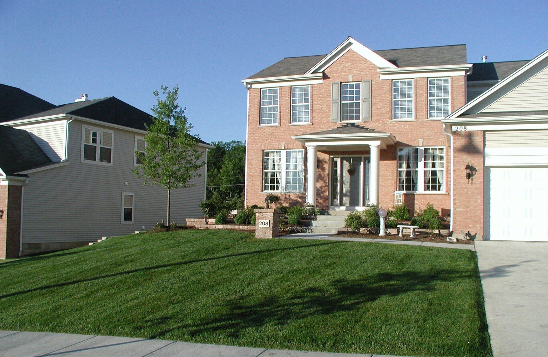 A large brick house with a lush green lawn in front of it