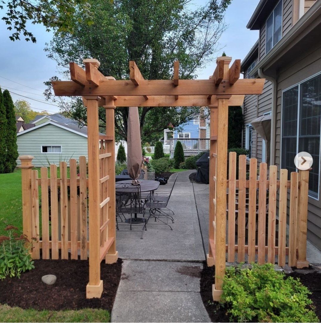 A wooden pergola is surrounded by a wooden fence