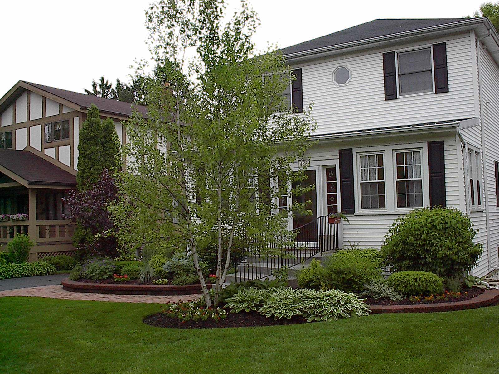 A white house with black shutters and a lush green lawn