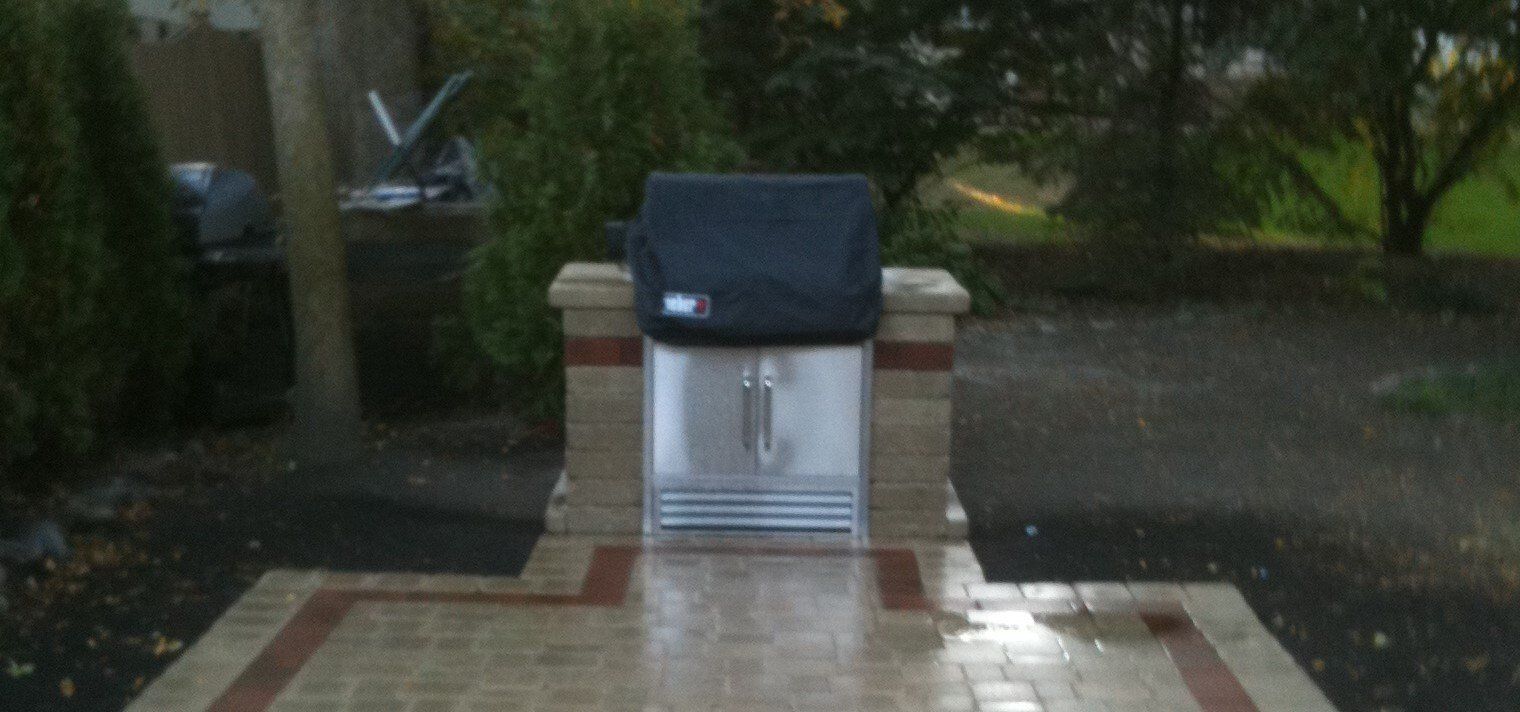 A grill is sitting on top of a brick patio.