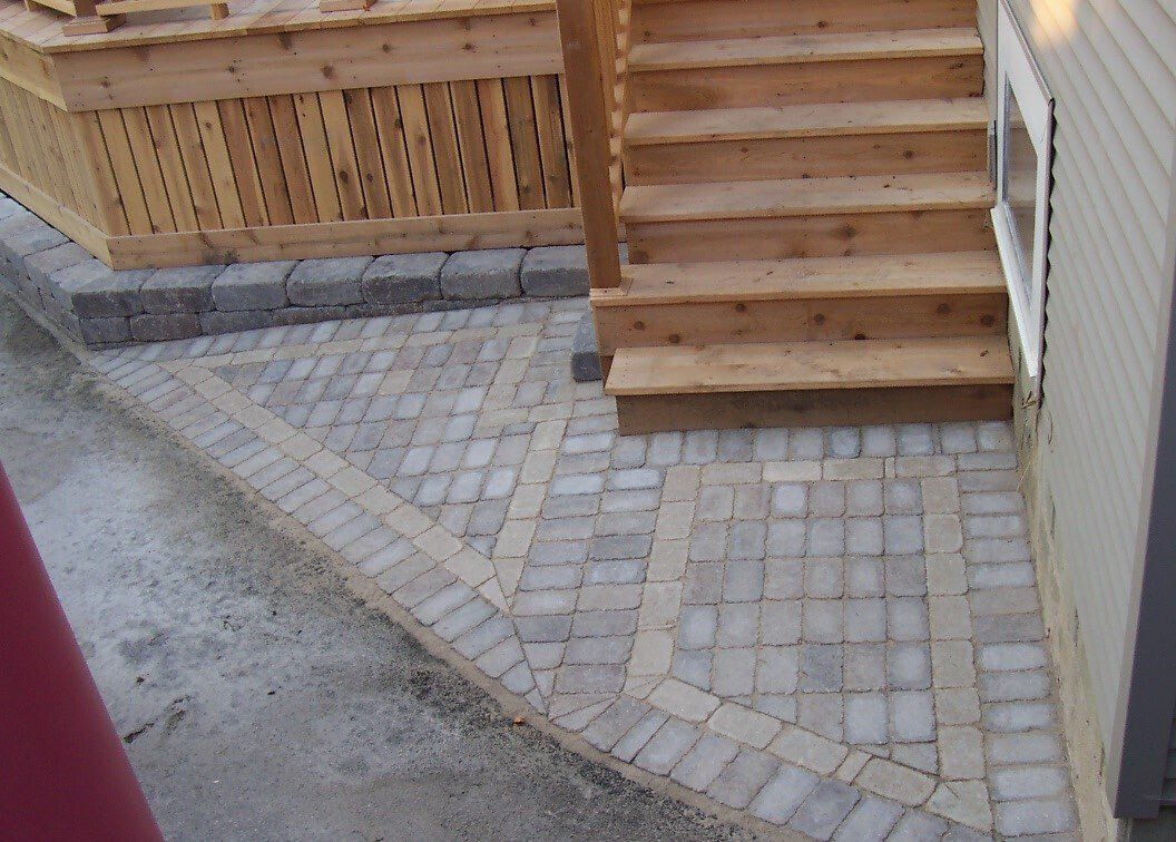 A brick walkway leading to a wooden deck and stairs