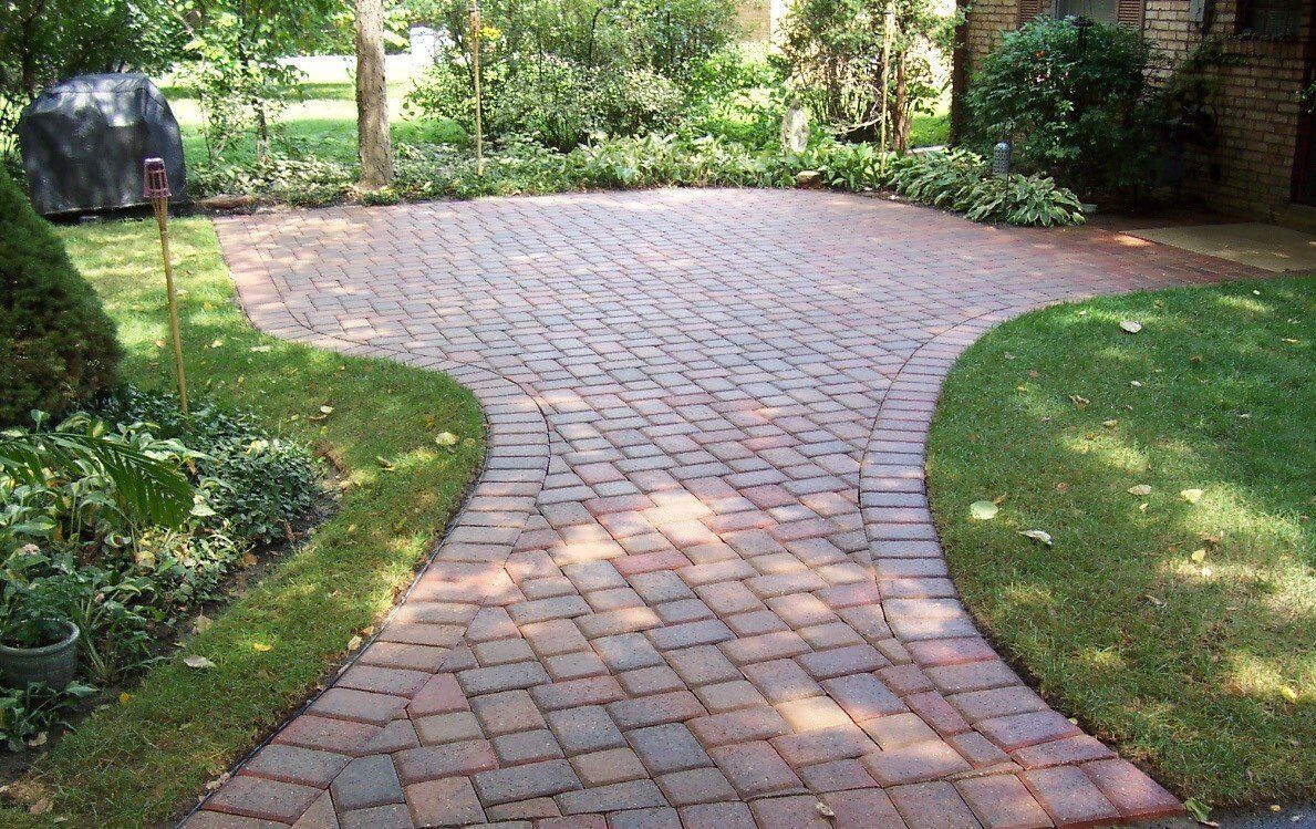 A brick walkway leading to a lush green yard