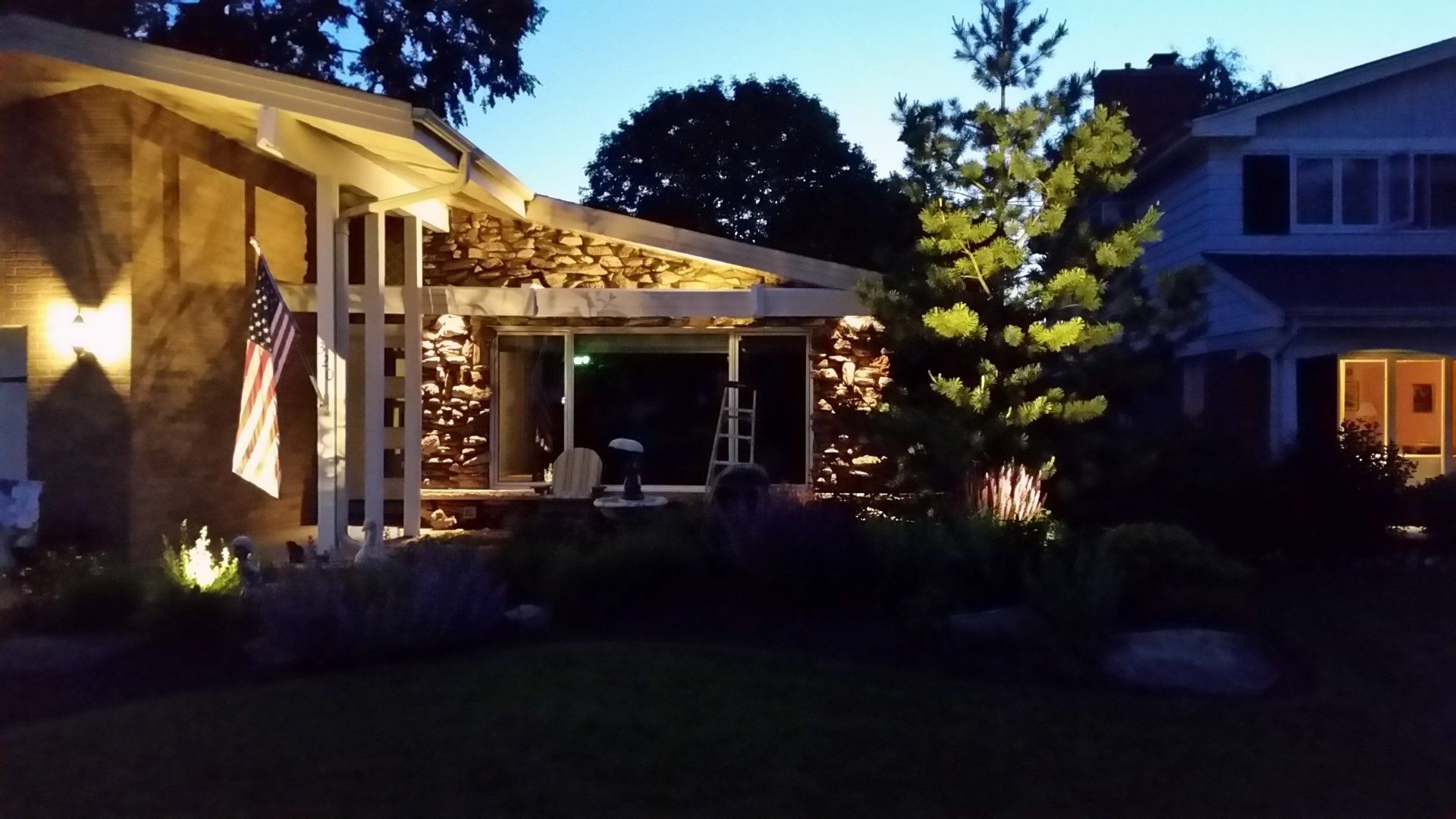A house with an american flag on the porch is lit up at night